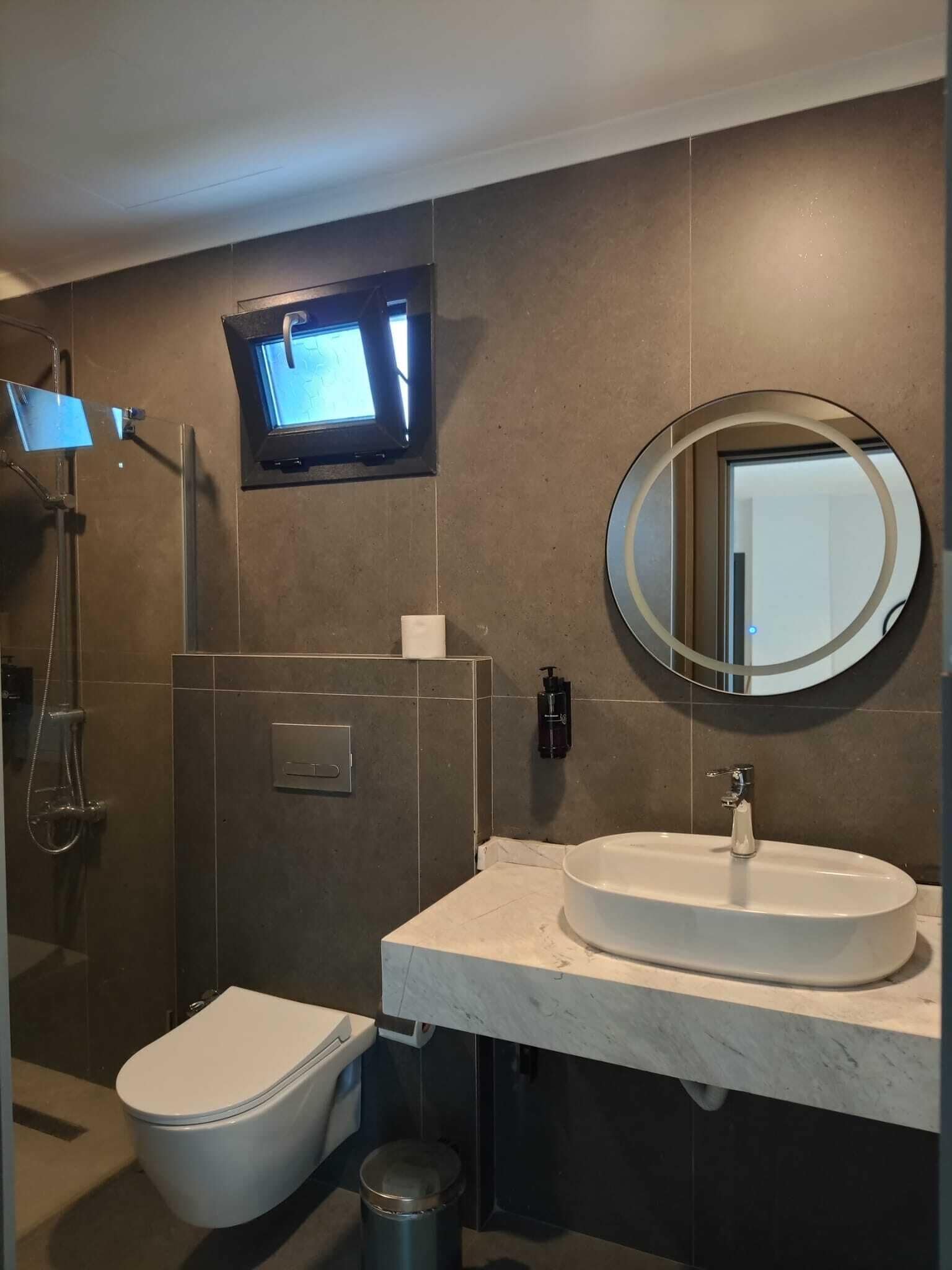 A modern bathroom with a toilet, sink, and shower.