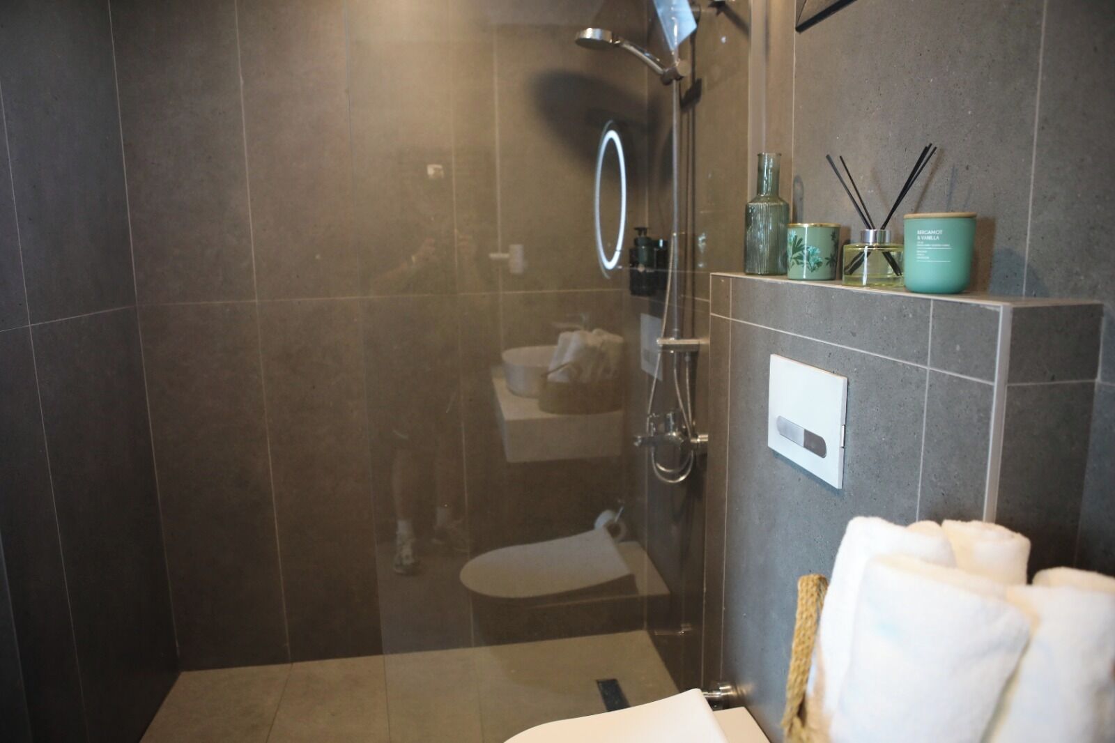 Un baño moderno con ducha de vidrio, inodoro y tocador con espejo.
