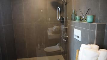 Un baño moderno con ducha de vidrio, inodoro y tocador con espejo.
