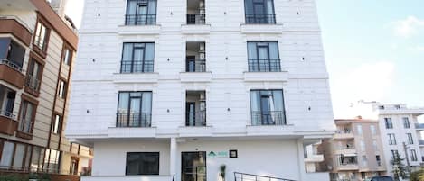 Ein mehrstöckiges Gebäude mit einer schlichten Fassade, einem zentralen Eingang und einer Treppe, die zum Eingang führt.