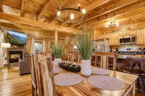 A wooden interior with a dining area, kitchen, and fireplace. - Gatlinburg Getaway - Downtown, Hot Tub, Theatre (Gatlinburg)
