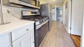 A kitchen with white cabinets, a stainless steel stove, and a microwave.