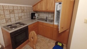 Una cocina compacta con armarios de madera, un lavamanos empotrado, una estufa y un refrigerador.