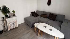 A modern living room with a grey sofa, a small white table, and a decorative cabinet. - Cool 1-bedroom apartment in Paris Bercy (Paris)