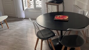 A dining area with a round table, two chairs, a television on a stand, and a window with curtains. - Cool 1-bedroom apartment in Paris Bercy (Paris)