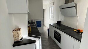 A modern kitchen with white cabinets, a black countertop, and a stainless steel range hood. - Cool 1-bedroom apartment in Paris Bercy (Paris)