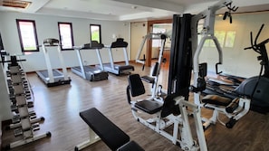 A gym with treadmills, weight machines, and a bench.