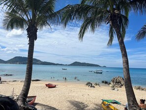 A beach with palm trees, boats, and people swimming. - Fantastic apartment with AC and great pool in Kalim Patong by the Sea (Tambon Patong)