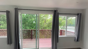 A room with a sliding glass door leading to a deck with a red lattice railing.