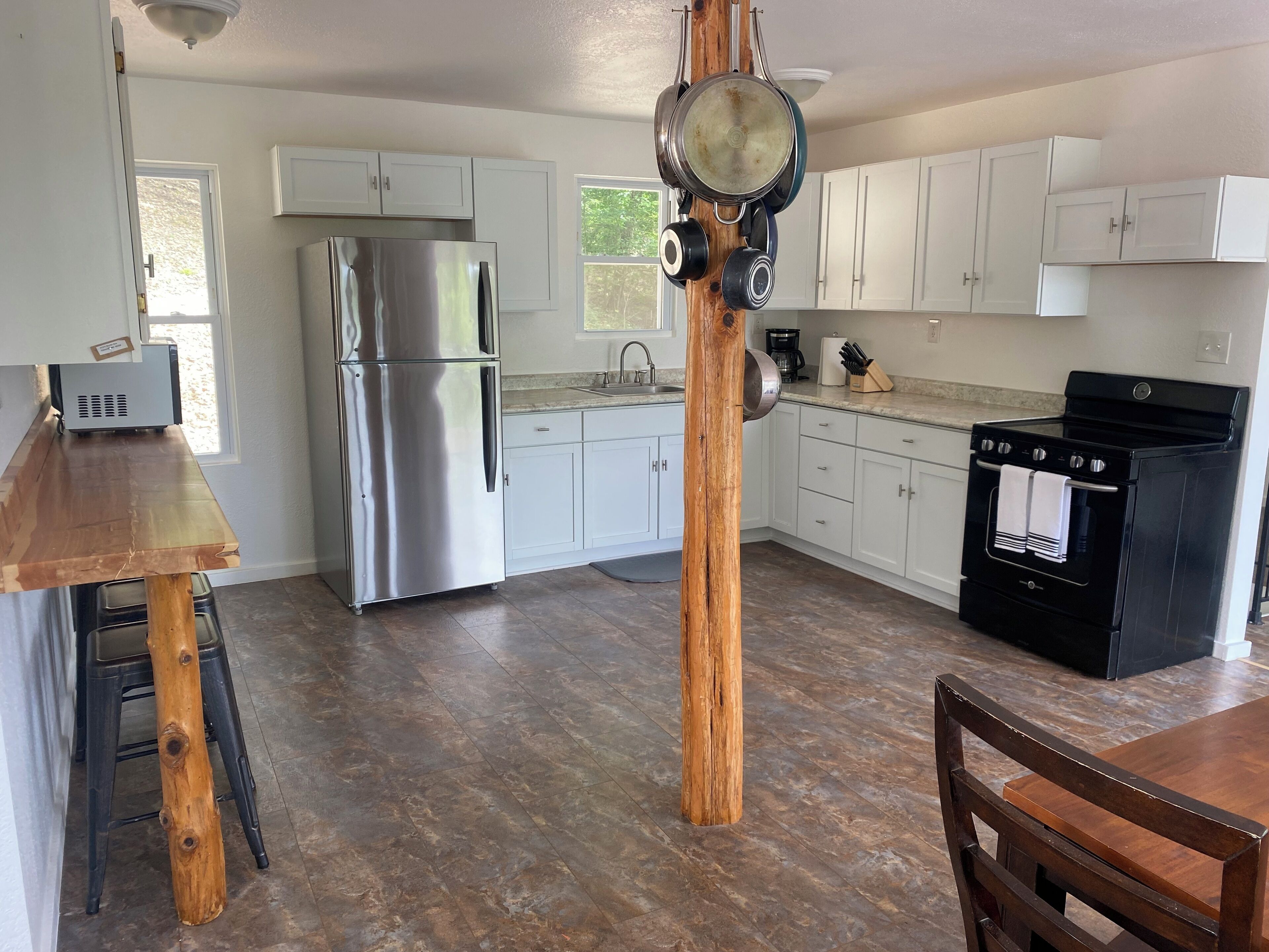 A kitchen with white cabinets, a stainless steel refrigerator, a black oven, and a wooden dining table.