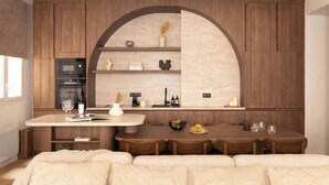 Una cocina moderna con armarios de madera, un microondas integrado y un comedor con una mesa redonda y sillas.