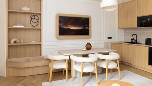 A modern kitchen with wooden cabinets, a dining table with white chairs, and a large painting on the wall. - Splendid Apartment 2BR 6P Palais Royal with AC (Paris)
