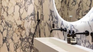 A modern bathroom with a marble backsplash, a freestanding sink, and a curved mirror. - Splendid Apartment 2BR 6P Palais Royal with AC (Paris)