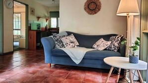 Un salon avec un canapé bleu, une table ronde et une lampe.