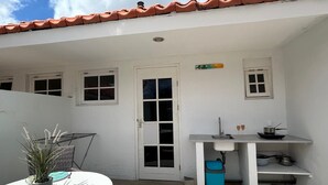 Eine kleine Küche mit weißen Wänden, einem Ziegeldach, einem Fenster und einer Tür.