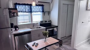 Una cocina compacta equipada con refrigerador, estufa, lavamanos y un comedor con mesa y sillas.