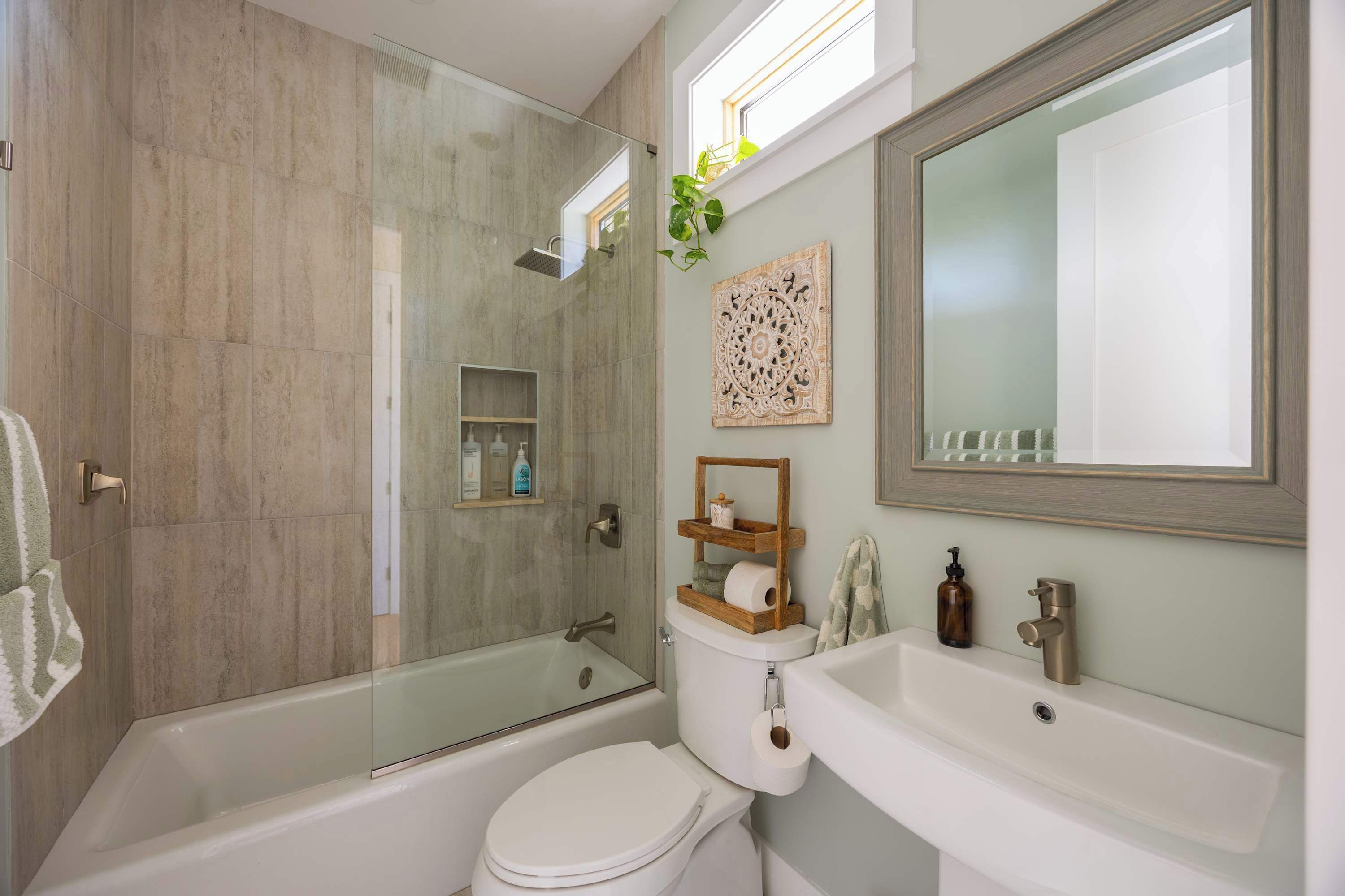 A modern bathroom with a glass-enclosed shower, a white toilet, and a sink with a mirror above it.