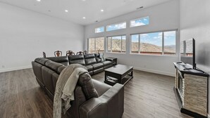 A spacious living room with a sectional sofa, a coffee table, and a TV stand. Large windows offer a view of a desert landscape. - Welcoming 3-bedroom suite in Gardnerville, NV near Topaz Lake. (Gardnerville)