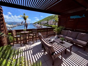 Een terras buiten met uitzicht op een jachthaven, een houten hek, een bank en een tafel.
