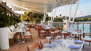 Een restaurant met gedekte tafels, met uitzicht op een waterpartij.