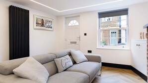 Un salon moderne avec un canapé, un tableau encadré, une fenêtre et une porte.