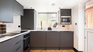 Une cuisine moderne équipée d’un four encastré, d’un four à micro-ondes et d’une fenêtre donnant sur l’extérieur.