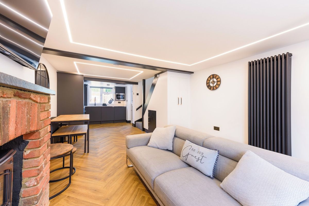 Ett modernt vardagsrum med en öppen spis, en soffa och en matplats.