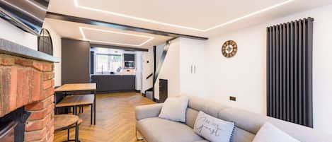 A modern living room with a fireplace, a sofa, and a dining area.