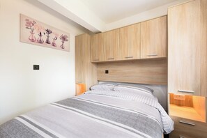 Un dormitorio con cama, armario de madera, mesitas de noche y una obra de arte floral en la pared.