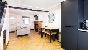 Un intérieur moderne comprenant un canapé, une table à manger et un coin cuisine avec un meuble noir et une machine à café.