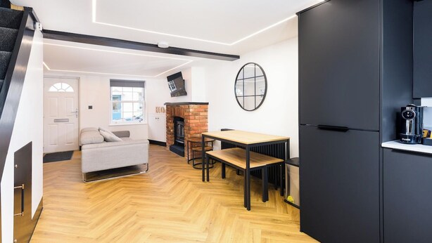 Um interior moderno com sofá, mesa de jantar e área de cozinha com armário preto e máquina de café.