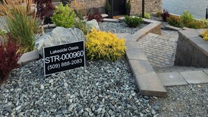 A house with a stone facade, a tiled roof, and a front yard with a sign reading "Lakeside Oasis STR-00960 (509) 888-2083". - Lake Chelan view home 1-bedroom in Manson with AC (Manson)