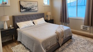 A bedroom with a large bed, a ceiling fan, a window with curtains, and a painting on the wall. - Lake Chelan view home 1-bedroom in Manson with AC (Manson)