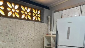 Eine Küche mit Gasherd, Backofen, weißem Kühlschrank, gefliestem Fliesenspiegel und einer Schrankwand.
