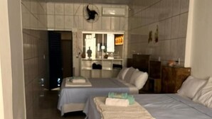 Ein Hotelzimmer mit zwei Betten, einem Badezimmer und einer Küchenzeile.