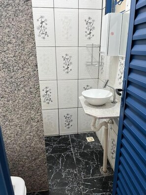 Une salle de bain avec un lavabo blanc, un sol en marbre noir et des carreaux à motifs floraux.