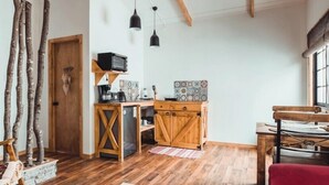 A rustic kitchen with wooden cabinets, a built-in dishwasher, and a small countertop. There are wooden beams on the ceiling and a window with a view of the outdoors. - Hostal Lago Cóndor (Natales)