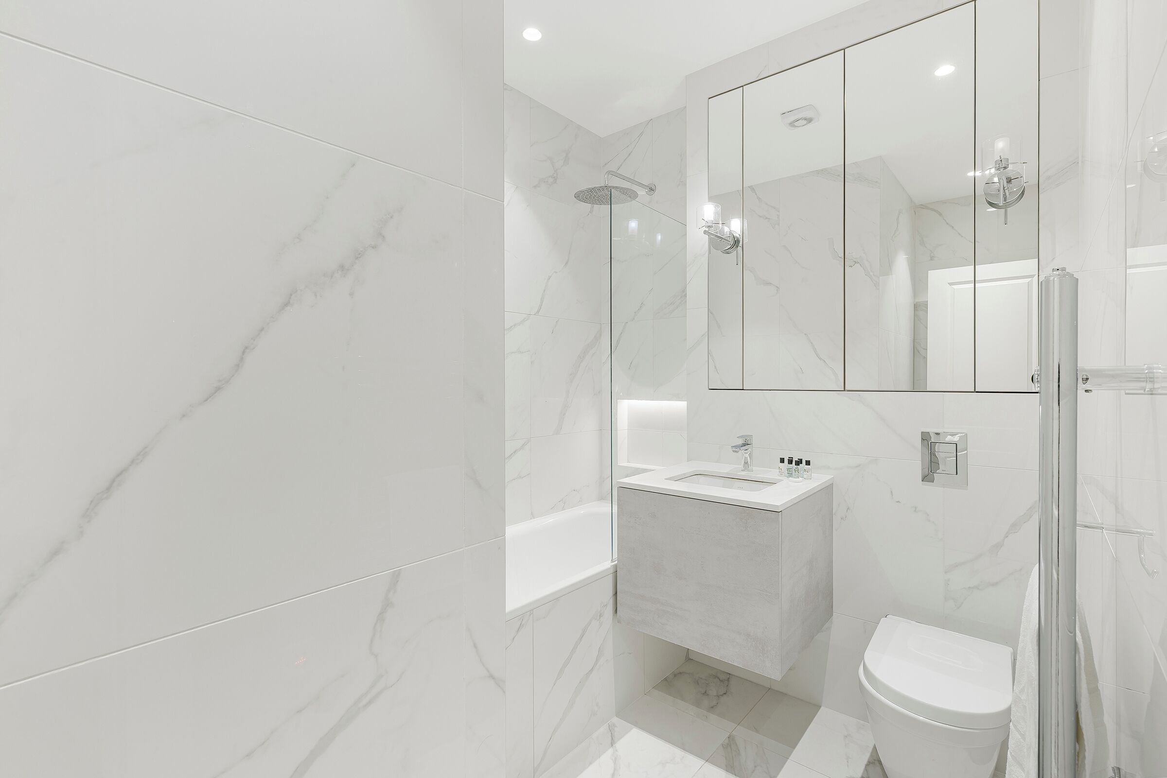 A modern bathroom with a glass shower enclosure, a white sink, and a toilet.