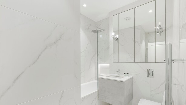 A modern bathroom with a glass shower enclosure, a white sink, and a toilet. - Collingham Road - 1 Bedroom Apartment III (London)