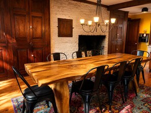 A dining area with a wooden table and chairs, a brick wall, and a fireplace. - New! A Waterfront Retreat on 14 Acres with 7 Bedrooms That Sleeps 13! (Stella)