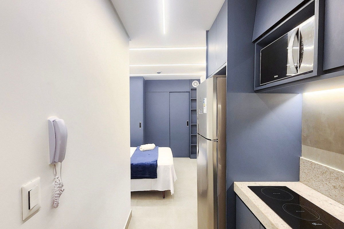 Une chambre d’hôtel moderne équipée d’un lit, d’un minibar, d’un four à micro-ondes intégré et d’un téléphone.