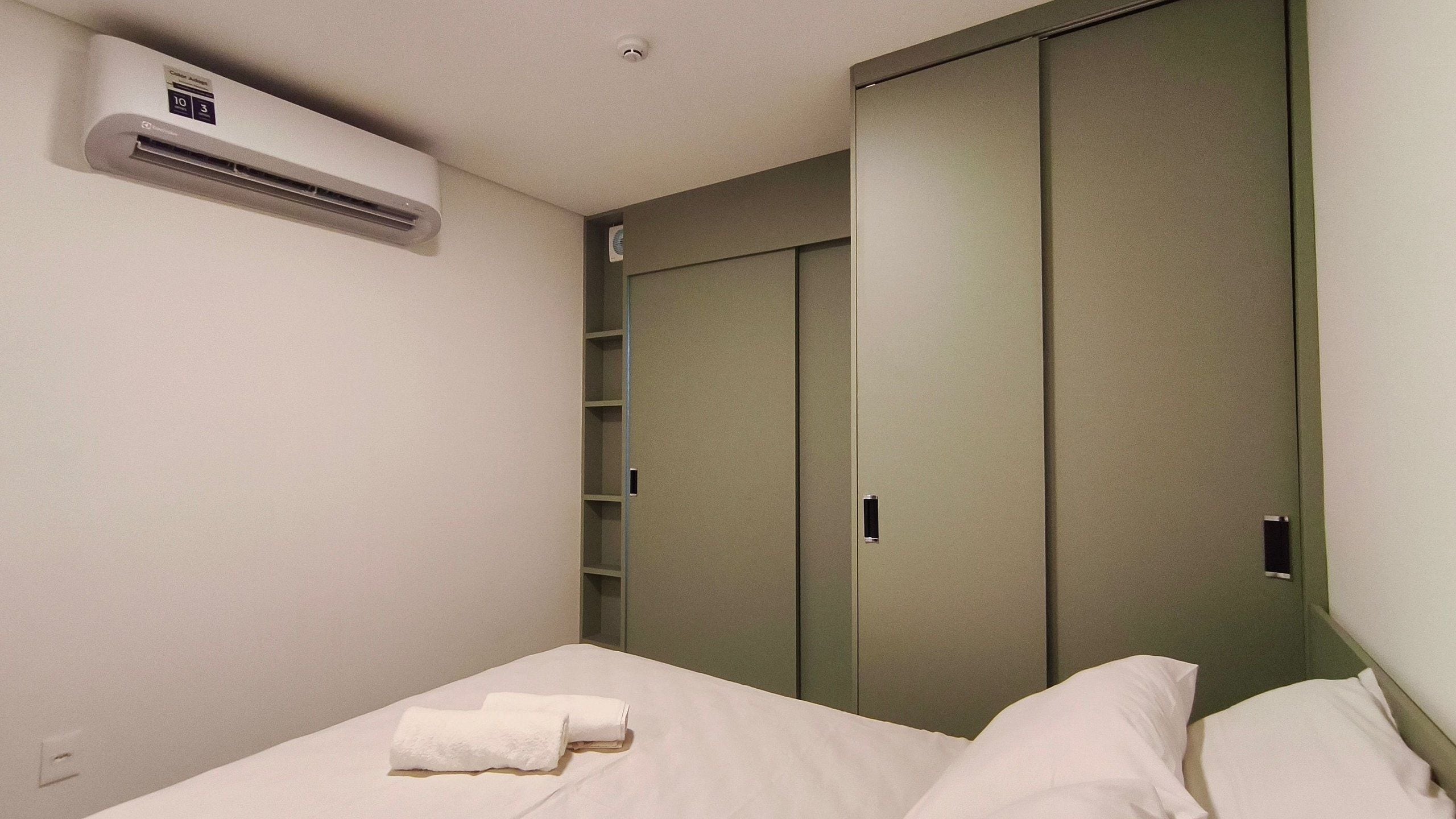 Une chambre à coucher comprenant un lit, une armoire et un appareil de climatisation.