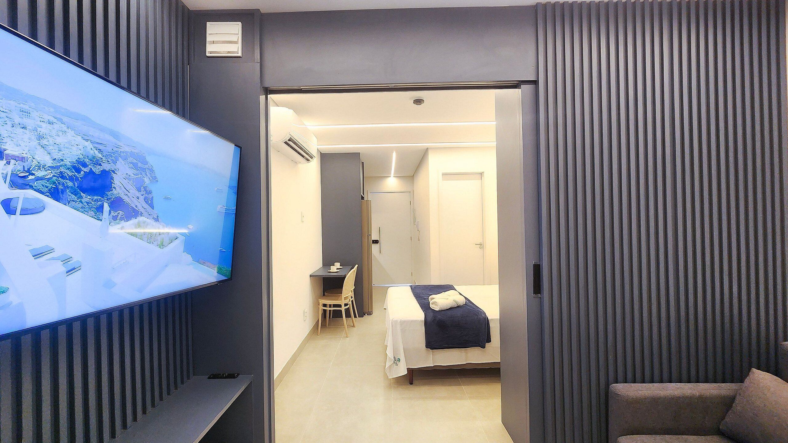 A hotel room with a TV, a bed, a desk, and a chair.