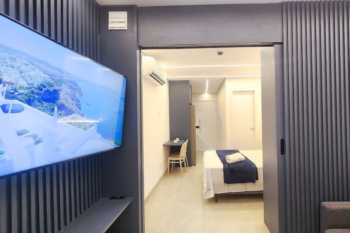 A hotel room with a TV, a bed, a desk, and a chair.