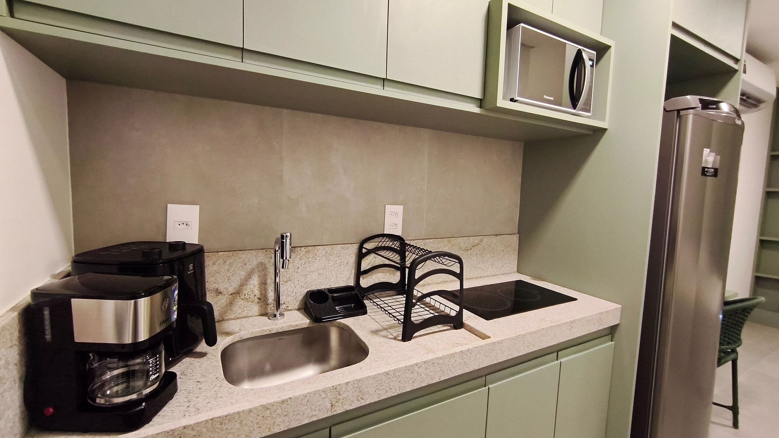A kitchen with a coffee maker, sink, and a microwave.