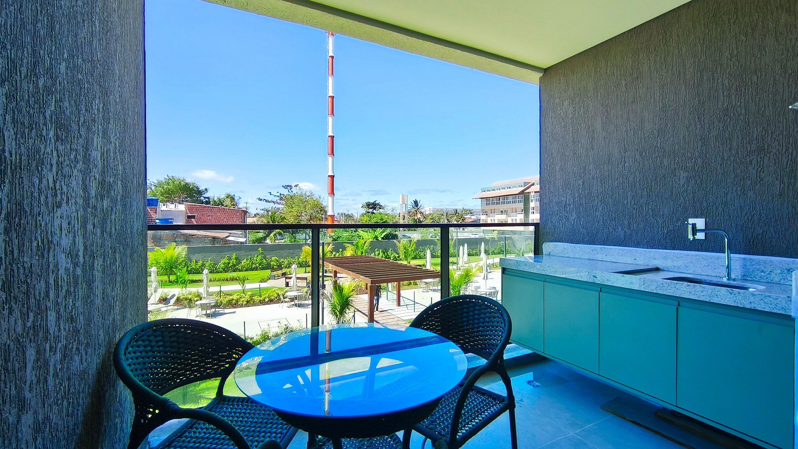 Een balkon met een tafel en stoelen, een keukenhoek en uitzicht op een stadsbeeld.