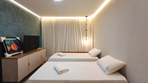 Quarto de hotel com duas camas, televisão de tela plana e um quadro na parede.