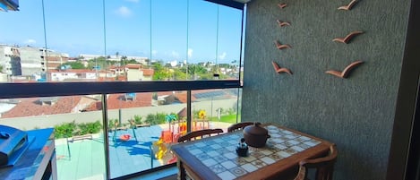 A balcony with a view of a residential area, a tiled table with a teapot, and a wall with bird-shaped decorations.