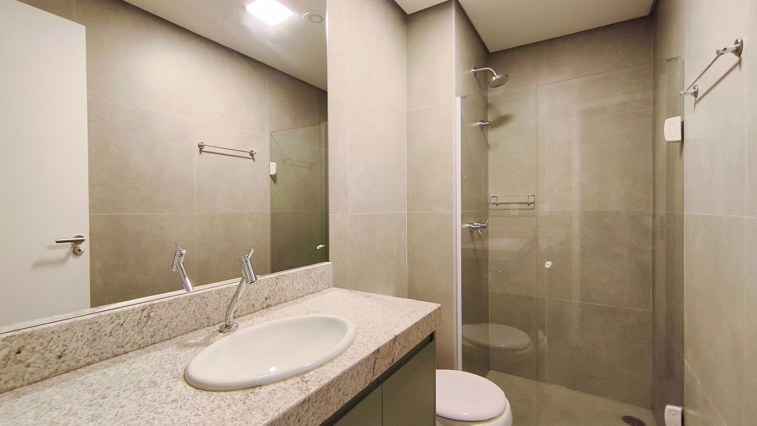 Un baño con lavamanos, espejo, ducha e inodoro.
