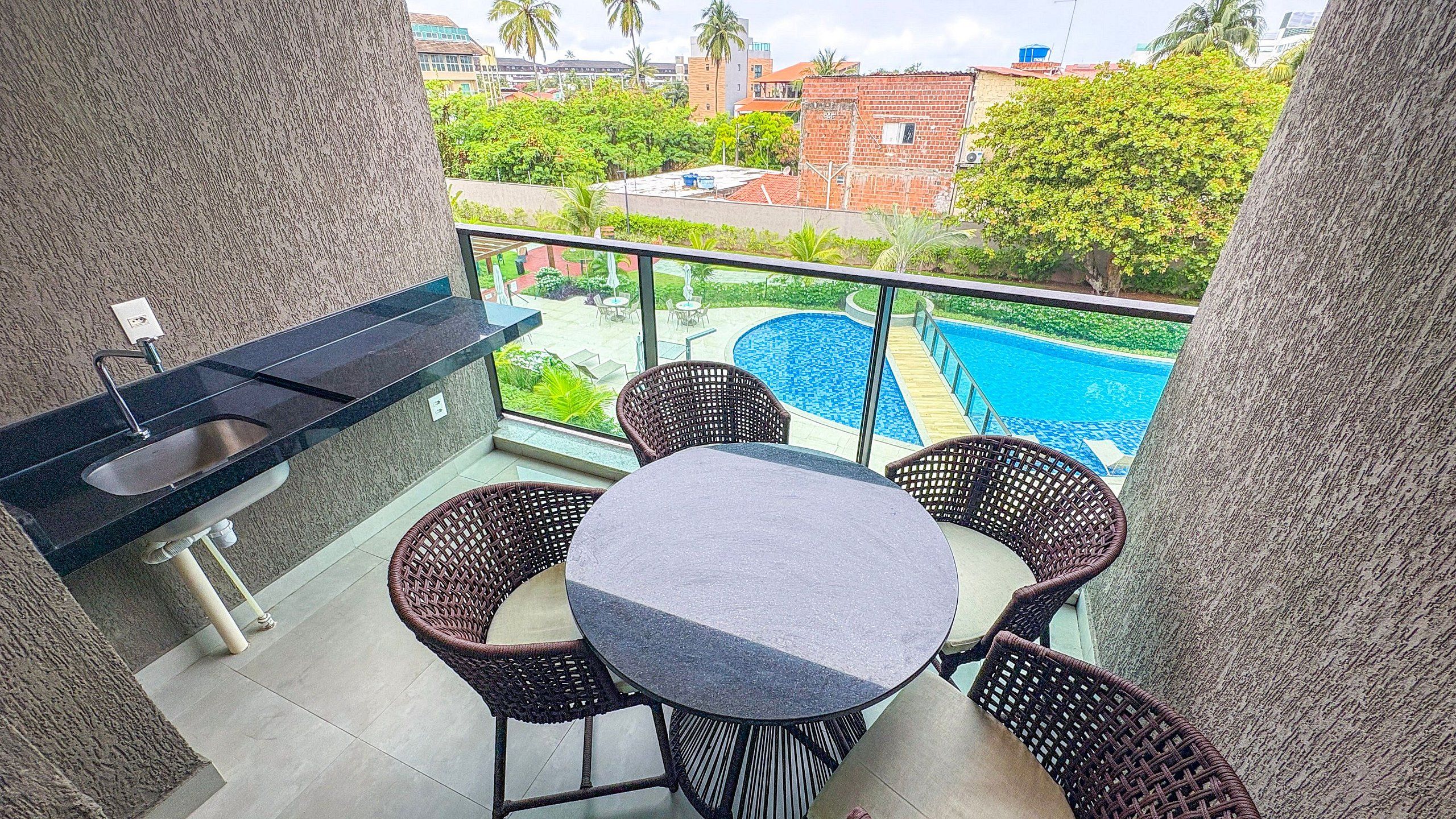 A balcony with a pool, outdoor furniture, and a view of buildings.